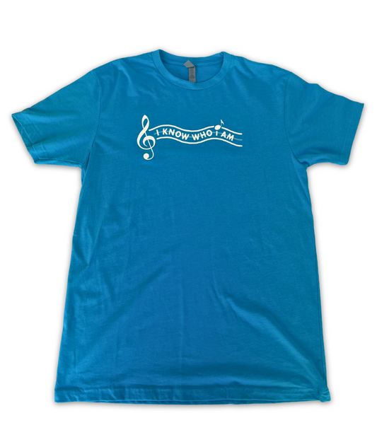 Image of a blue t shirt with the text "I Know Who I Am" written on the front, next to a large treble clef