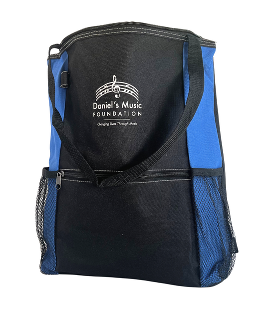 Image of a blue and black tote bag with a zipper in the front and two mesh pockets on the side. Daniel's Music Foundation is written on the front, underneath a stylized music ledger line.