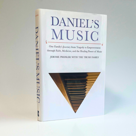 Image of the "Daniel's Music" biography, standing on it's side. The cover features an inverted triangle containing a photo of a piano keyboard